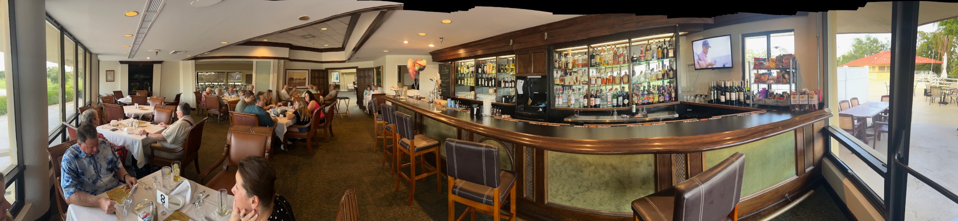 Interior view of a dining area with tables, a bar, and patrons enjoying their meals.