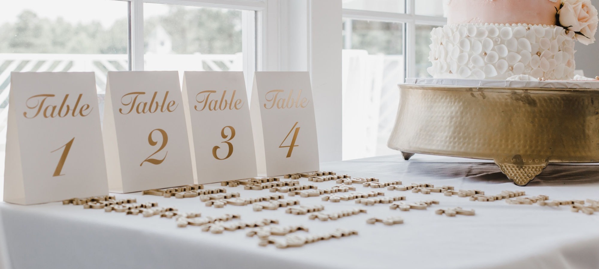Table numbers 1 to 4 displayed on a table with decorative wooden pieces and a cake in the background.